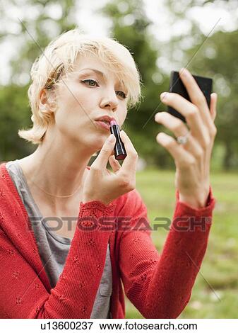 Woman holding mirror and using lipstick View Large Photo Image Stock Photo - Woman holding mirror and using lipstick. Fotosearch