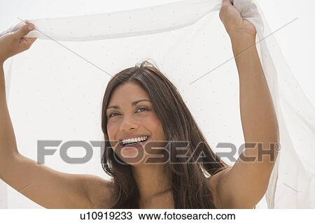 Stock Image - Woman holding white cloth over head. Fotosearch