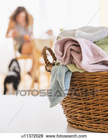 Stock Photo - Woman in kitchen with laundry basket in foreground. Fotosearch