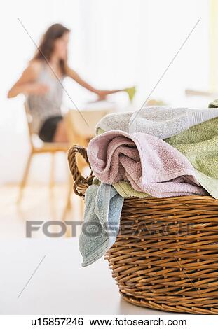 Stock Photograph - Woman in kitchen with laundry basket in foreground. Fotosearch