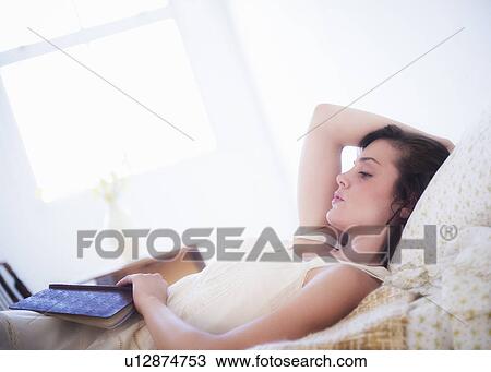 Woman in white chemise laying in bed and holding book View Large Photo Image Stock Image - Woman in white chemise laying in bed and holding book. Fotosearch