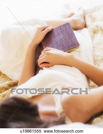 Woman in white chemise laying in bed and holding book View Large Photo Image Stock Photography - Woman in white chemise laying in bed and holding book. Fotosearch