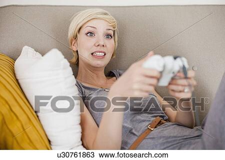 Woman laying on sofa and playing video game View Large Photo Image Stock Image - Woman laying on sofa and playing video game. Fotosearch