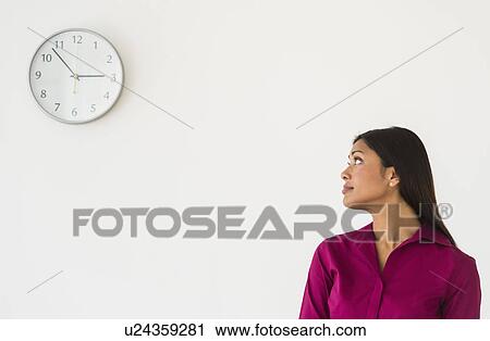 Woman looking at clock on wall View Large Photo Image Stock Image - Woman looking at clock on wall. Fotosearch