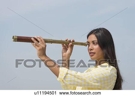 Stock Image - Woman looking through telescope. Fotosearch