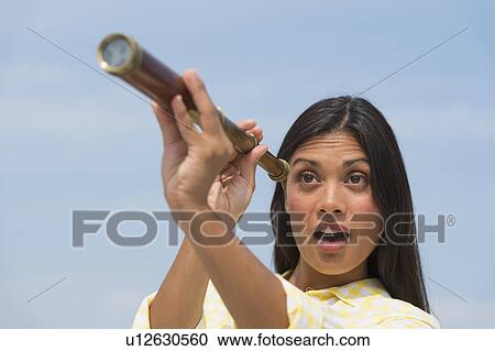 Stock Image - Woman looking through telescope. Fotosearch