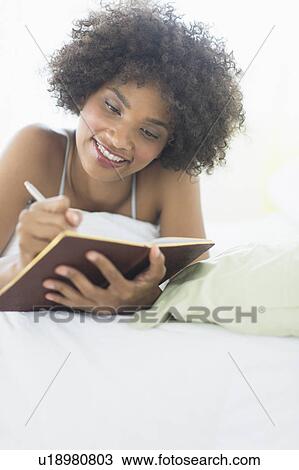 Woman lying on bed writing diary View Large Photo Image Stock Image - Woman lying on bed writing diary. Fotosearch