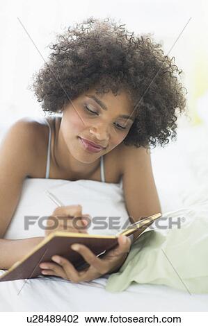 Woman lying on bed writing diary View Large Photo Image Stock Image - Woman lying on bed writing diary. Fotosearch