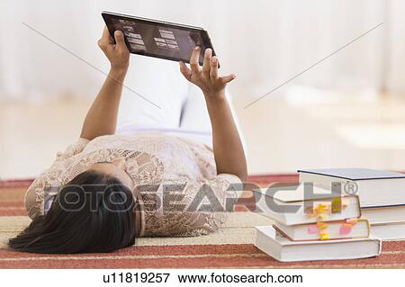 Woman lying on floor and using tablet PC View Large Photo Image Stock Photo - Woman lying on floor and using tablet PC. Fotosearch