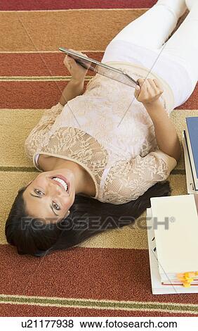Woman lying on floor and using tablet PC View Large Photo Image Stock Photo - Woman lying on floor and using tablet PC. Fotosearch