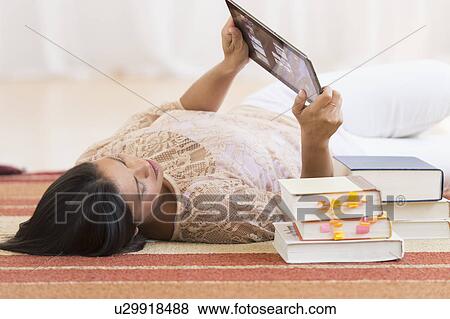 Stock Photo - Woman lying on floor and using tablet PC. Fotosearch