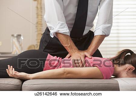 Woman lying on her front side getting adjusted by chiropractor View Large Photo Image Stock Photograph - Woman lying on her front side getting adjusted by chiropractor. Fotosearch