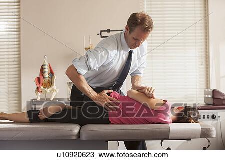 Stock Image - Woman lying on side getting adjusted by chiropractor. Fotosearch