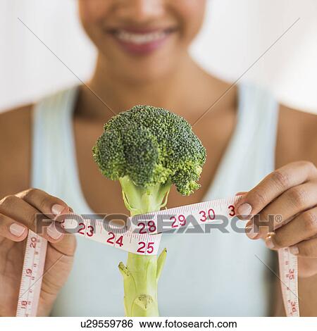 Stock Photograph - Woman measuring broccoli . Fotosearch