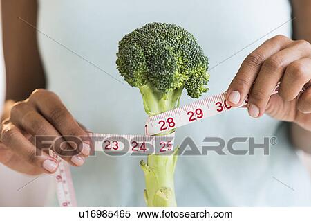 Stock Photography - Woman measuring broccoli . Fotosearch