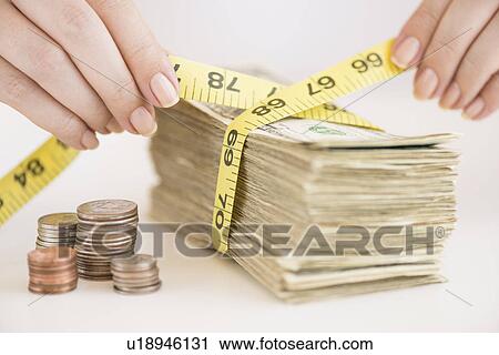 Stock Image - Woman measuring bunch of banknotes. Fotosearch