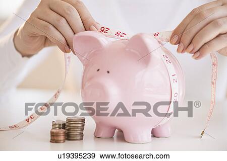Woman measuring piggybank View Large Photo Image Stock Photo - Woman measuring piggybank. Fotosearch