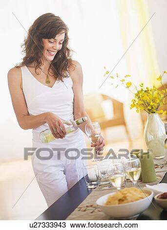 Stock Image - Woman pouring wine to glass. Fotosearch