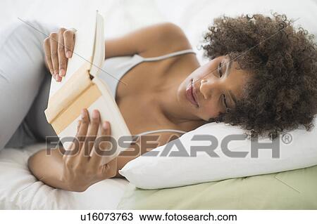 Stock Image - Woman reading in bed. Fotosearch