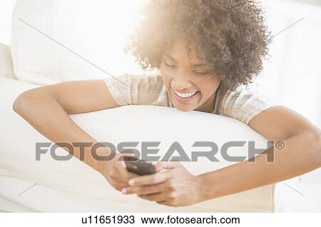 Woman relaxing on sofa using cell phone View Large Photo Image Stock Image - Woman relaxing on sofa using cell phone. Fotosearch