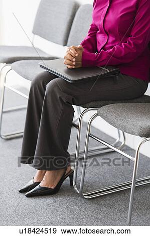 Stock Photo - Woman sitting in waiting room. Fotosearch