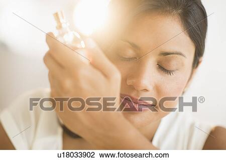 Stock Image - Woman smelling perfume on wrist. Fotosearch