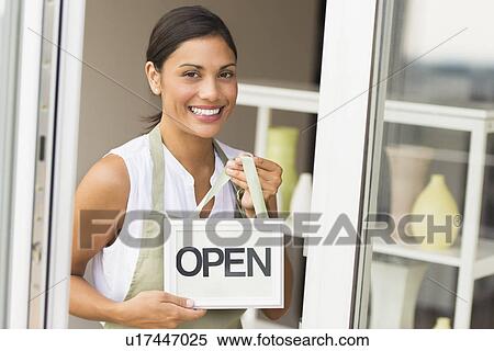 Woman standing in front of store and holding open sign View Large Photo Image Stock Photography - Woman standing in front of store and holding open sign. Fotosearch