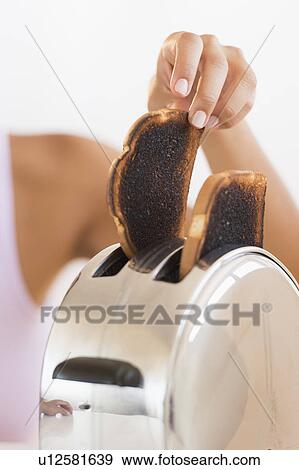 Woman taking burnt toast from toaster View Large Photo Image Stock Photo - Woman taking burnt toast from toaster. Fotosearch