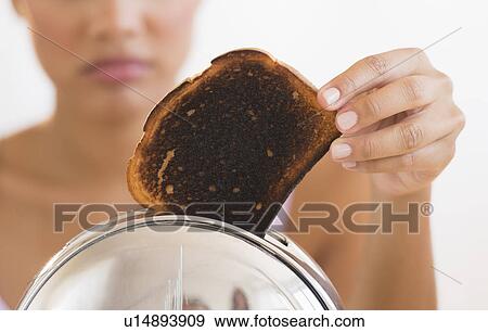 Stock Photo - Woman taking burnt toast from toaster. Fotosearch