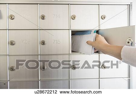 Stock Image - Woman taking letters from safety deposit box. Fotosearch
