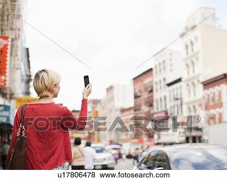 Woman taking picture with her mobile phone on street View Large Photo Image Stock Photo - Woman taking picture with her mobile phone on street. Fotosearch