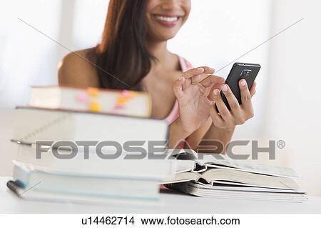 Picture - Woman text messaging while studying. Fotosearch