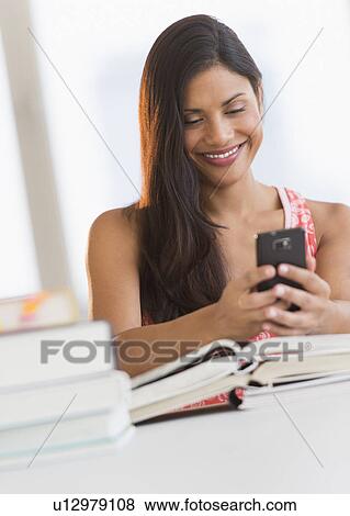 Stock Photo - Woman text messaging while studying. Fotosearch