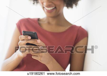 Stock Image - Woman using cell phone, studio shot. Fotosearch