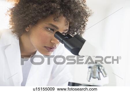 Stock Photo - Woman using microscope in laboratory. Fotosearch
