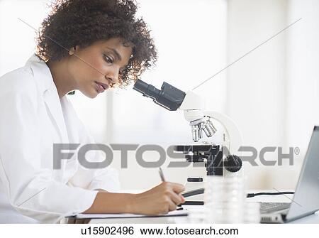 Stock Photograph - Woman using microscope in laboratory. Fotosearch