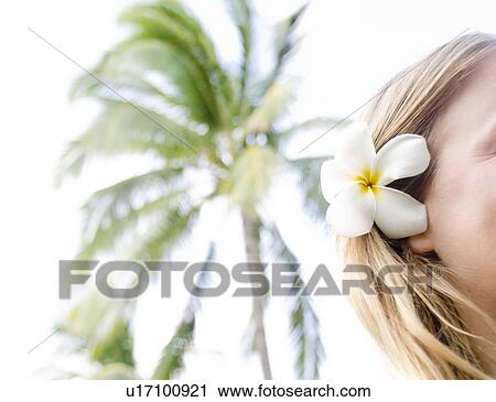 Stock Image - Woman wearing plumeria flower in hair. Fotosearch