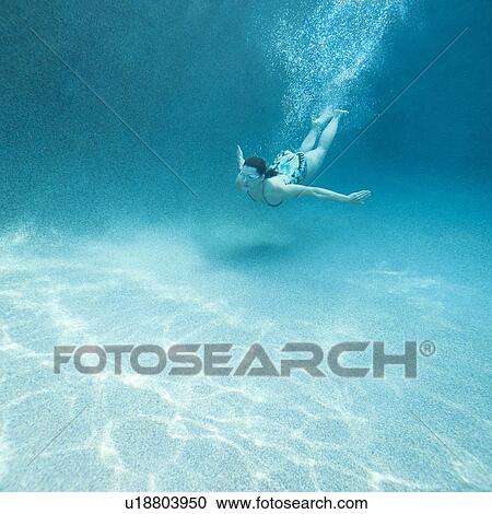 Stock Image - Young attractive woman diving in swimming pool. Fotosearch