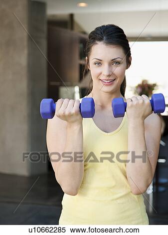 Stock Photography - Young attractive woman exercising with dumbbells. Fotosearch