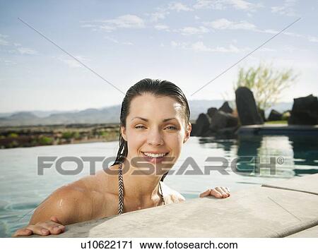 Young attractive woman leaning on edge of swimming pool View Large Photo Image Stock Image - Young attractive woman leaning on edge of swimming pool. Fotosearch