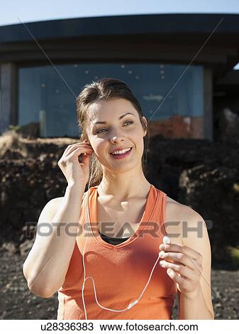 Young attractive woman plugging earphones in her ears View Large Photo Image Stock Image - Young attractive woman plugging earphones in her ears. Fotosearch