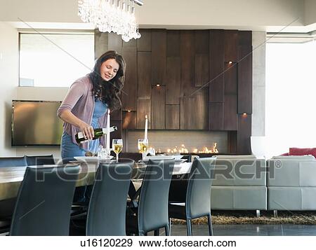 Stock Photo - Young attractive woman pouring champagne into glasses. Fotosearch