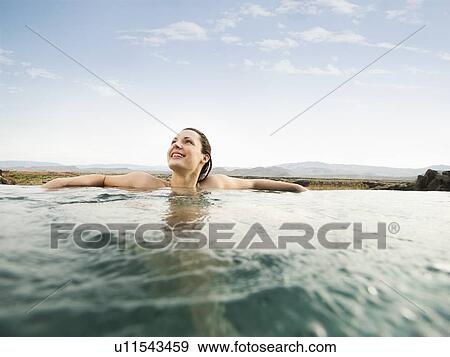 Stock Photo - Young attractive woman standing at edge of swimming pool. Fotosearch