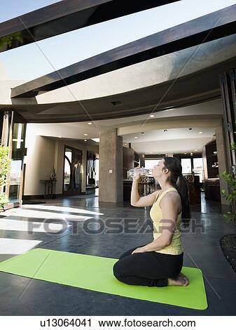 Young attractive woman taking a break in practicing yoga to drink some water View Large Photo Image Stock Image - Young attractive woman taking a break in practicing yoga to drink some water. Fotosearch