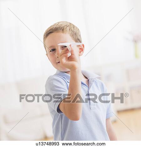 Stock Image - Young boy (6-7) playing with paper plane. Fotosearch
