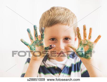 Stock Photo - Young boy (6-7) showing hands stained with paint. Fotosearch