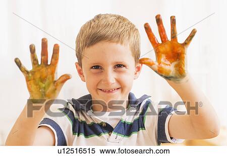 Stock Photography - Young boy (6-7) showing hands stained with paint. Fotosearch