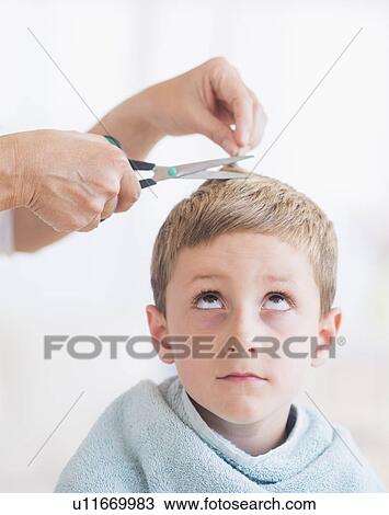 Stock Image - Young boy (6-7) undergoing haircut. Fotosearch