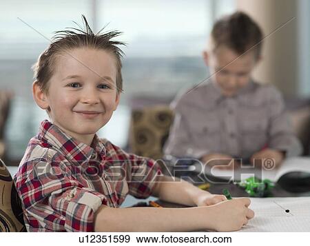Stock Photo - Young boys (6-7) doing homework at kitchen table. Fotosearch