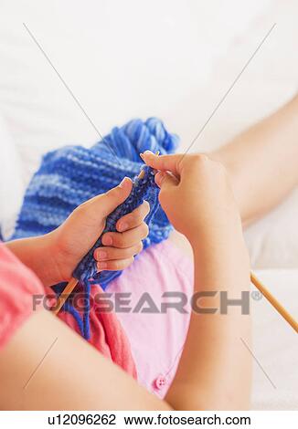 Stock Image - Young girl (8-9) knitting . Fotosearch